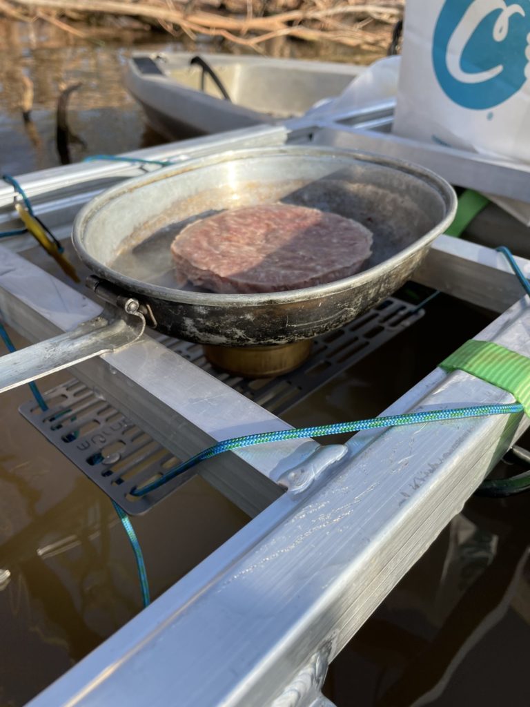Cooking a frozen meat puck over alcohol stove on world war II mess kit.